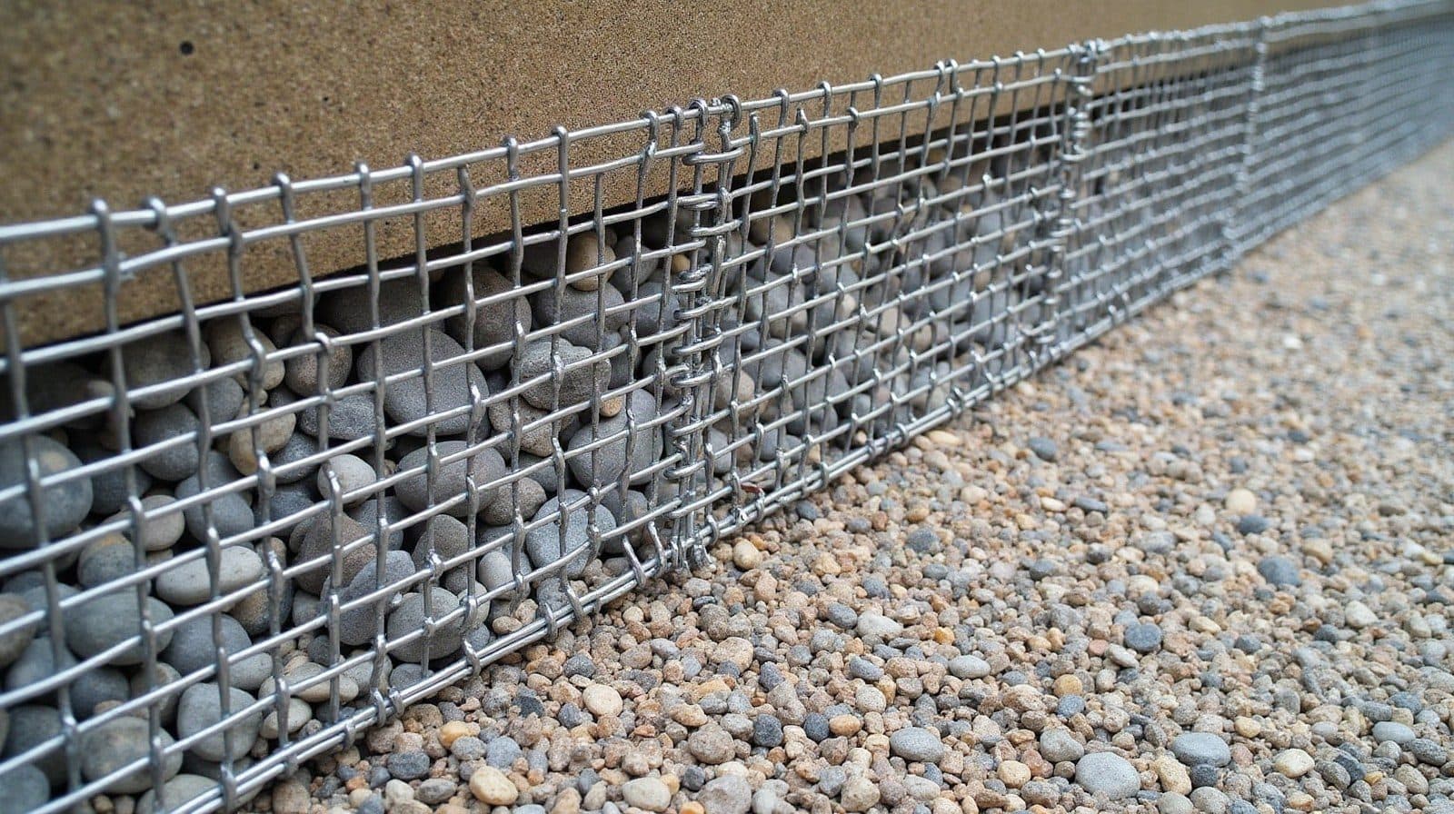 Cage de gabion remplie de pierres en cours de montage sur un terrain en pente